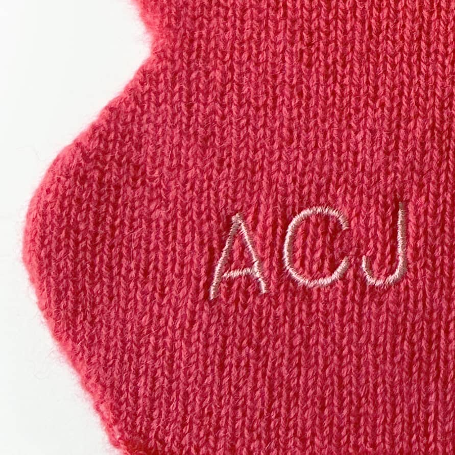Close up of embroidered personalisation of scallop edge cashmere scarf in red.