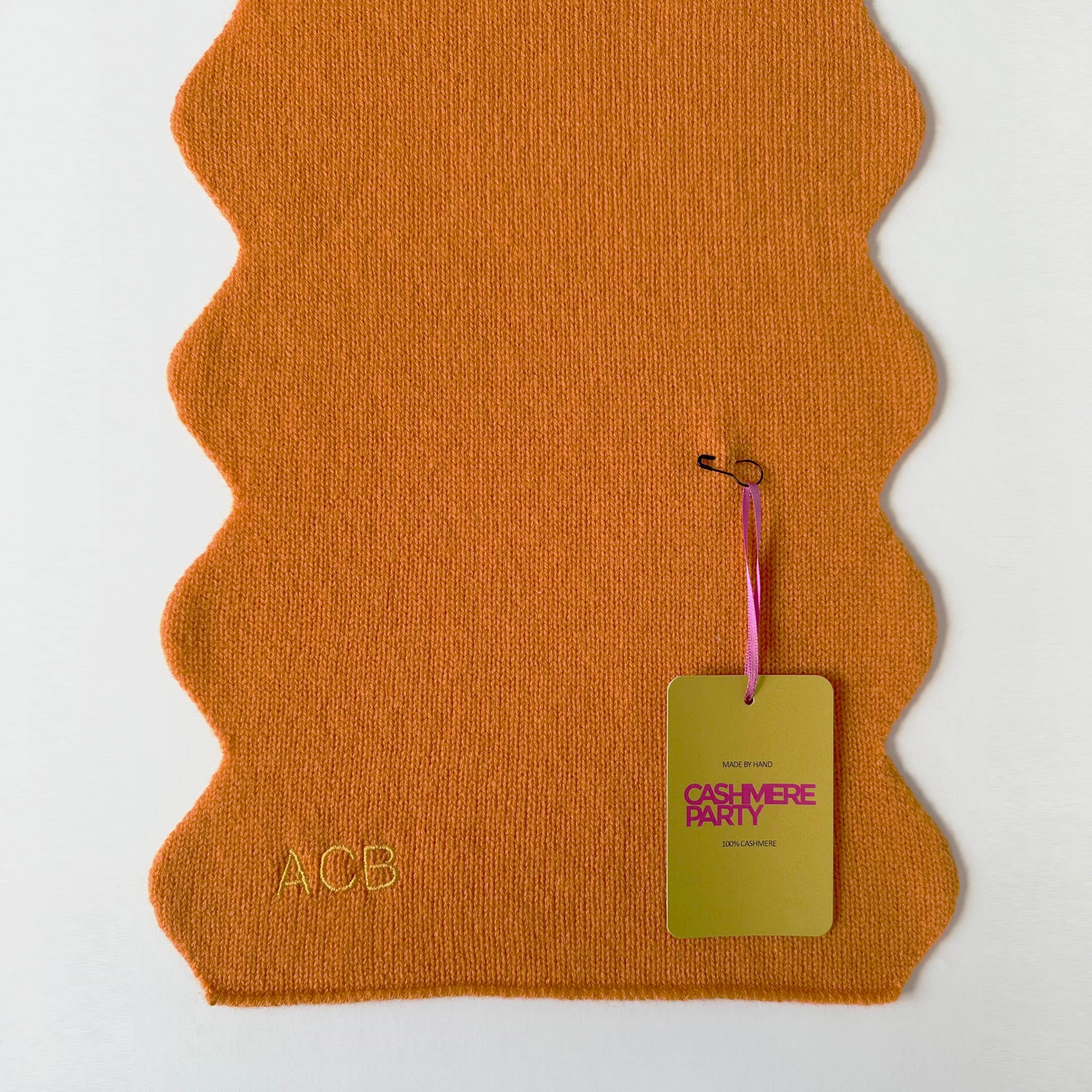 Pure cashmere scarf with scallop edges and personalisation.  Handmade knitted cashmere scarf in orange colour with Cashmere Party branded swing ticket.