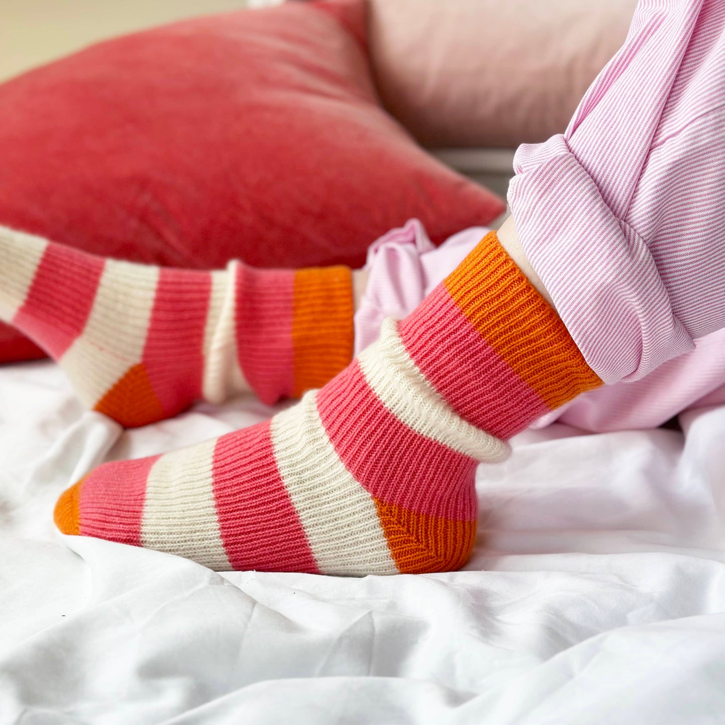 Bright Fun Cashmere socks on feet laying on bed.  Bold bright coloured stripes cashmere socks by Cashmere Party. 100% cashmere socks, thick and chunky warm socks.