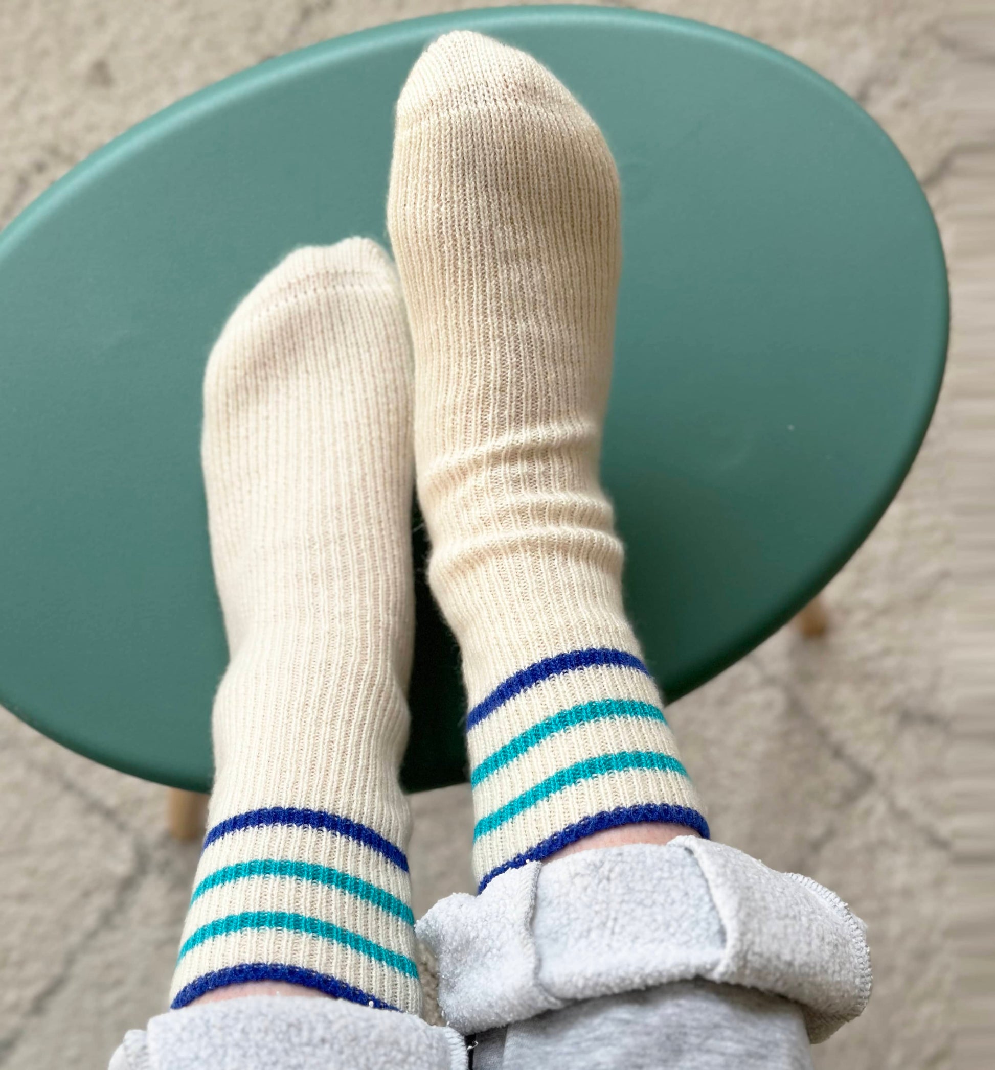 100% cashmere socks by Cashmere Party.  Fun modern handmade socks.  With blue sport stripes on feet with feet up on a stool