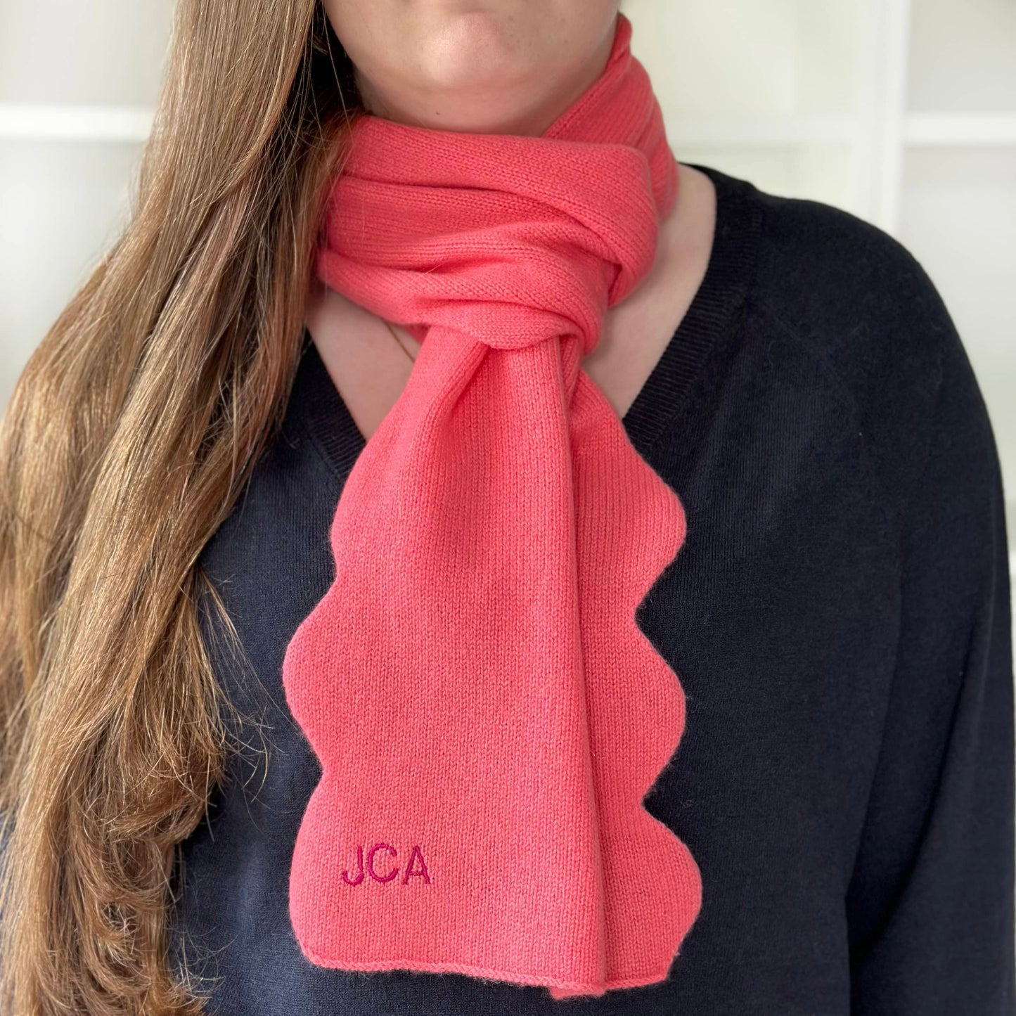 Close up of scallop edge cashmere scarf in coral colour.  100% cashmere scarf personalised with embroidered initials on woman.