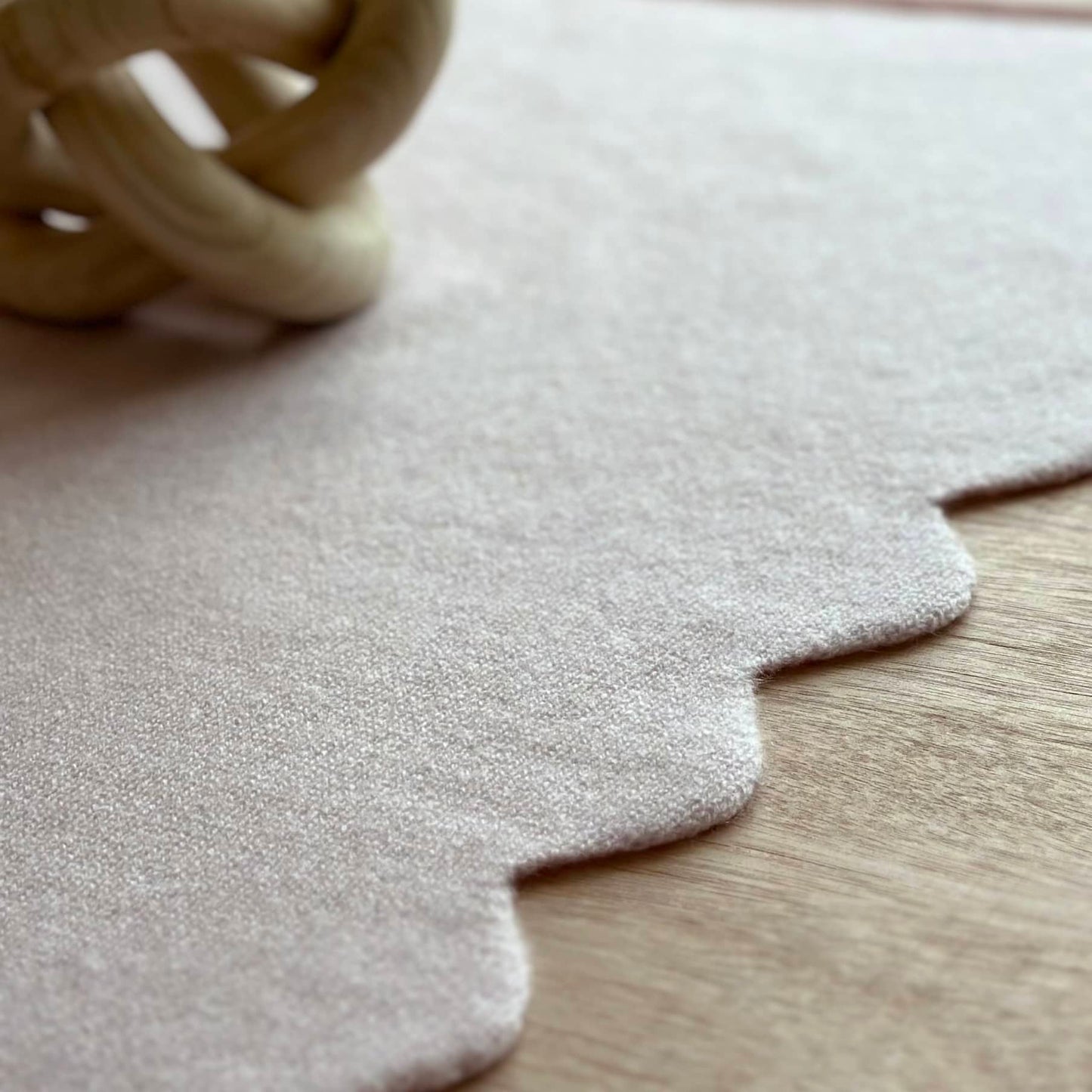 Close up detail of scallop edge baby blanket in pure cashmere with sun reflecting on the table.