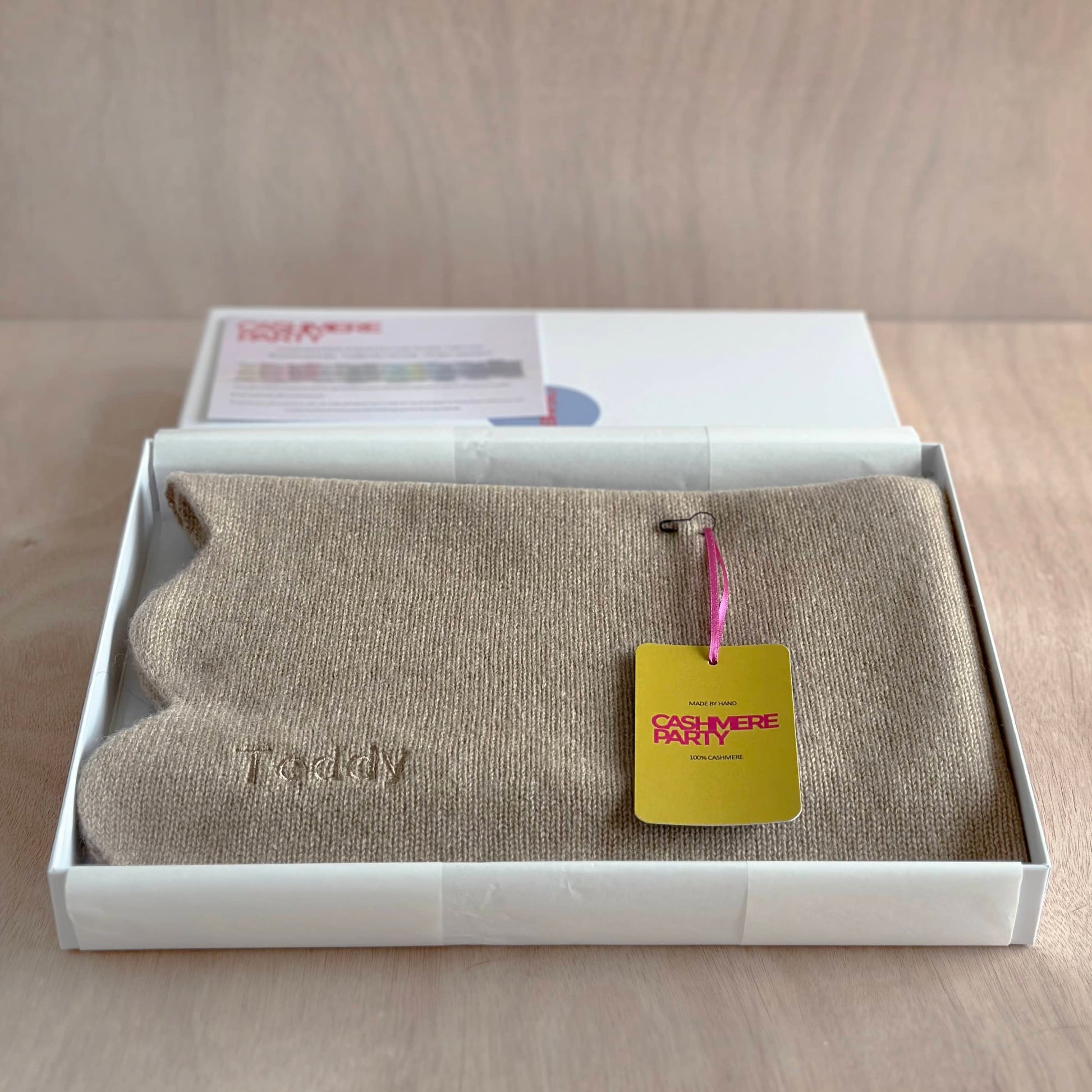 Scalloped edge baby blanket folded in a gift box with branded swing ticket by Cashmere Party.